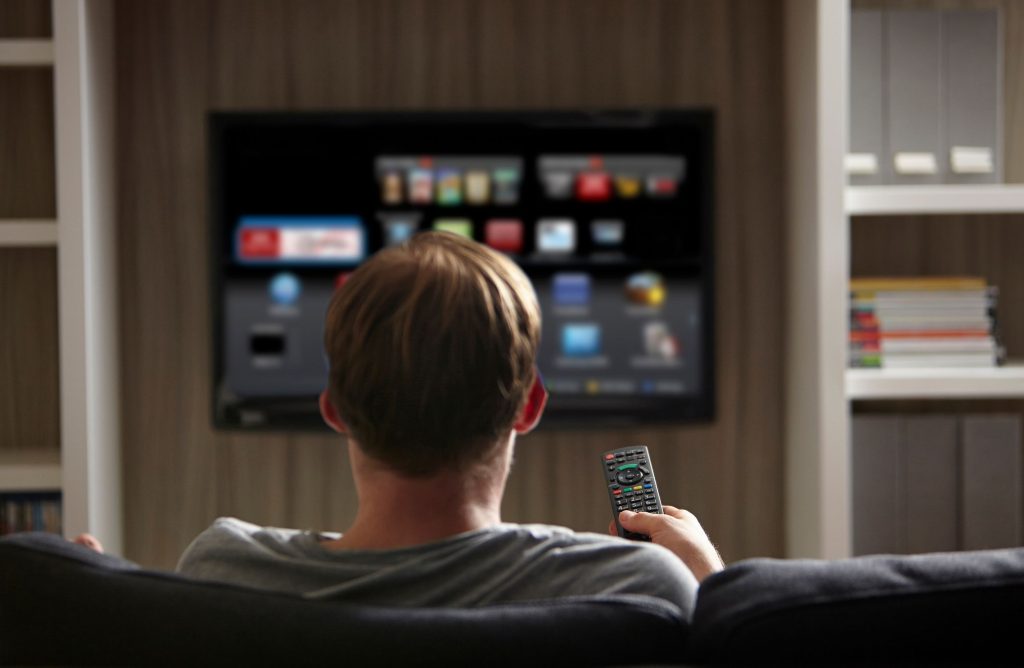 Man watching TV mounted to wall on a bracket