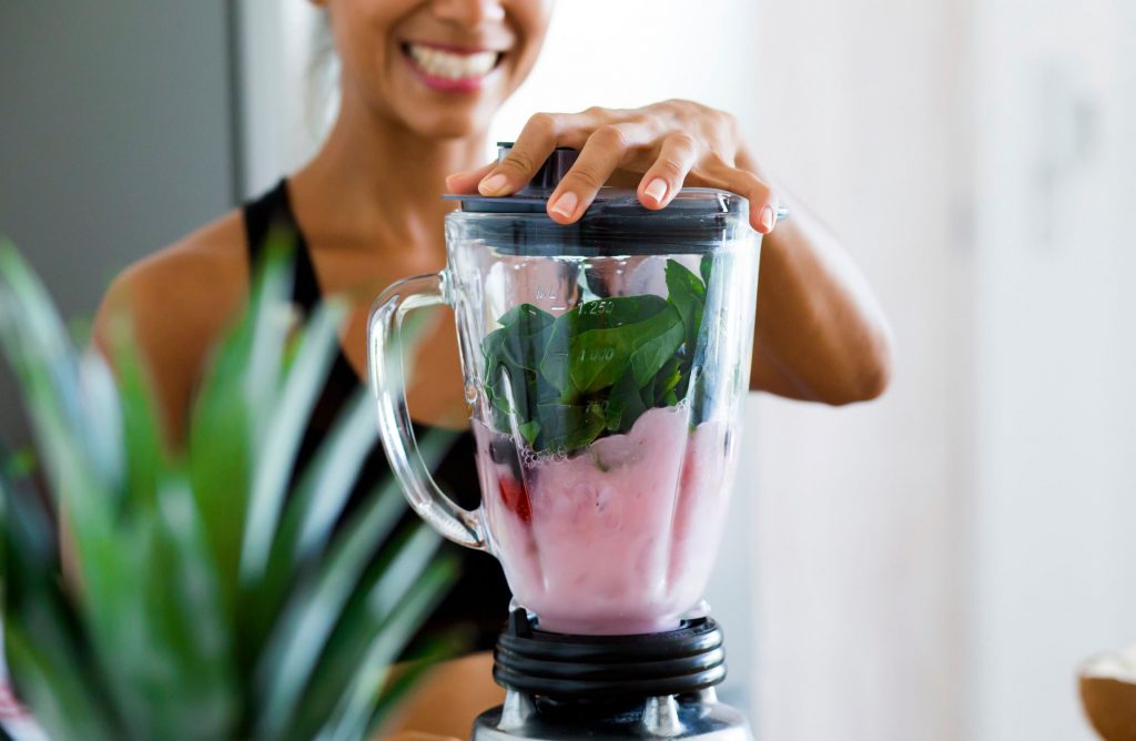 A woman using a blender to make a delicious smoothie