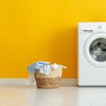 Washing machine with drip tray underneath and full laundry basket